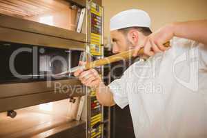 Baker taking bread out of oven