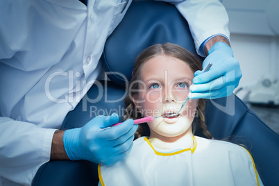 Male dentist examining girls teeth