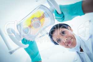 Low angle of female dentist adjusting light