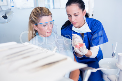 Dentist showing patient model of teeth