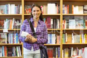 Smiling university student holding textbook