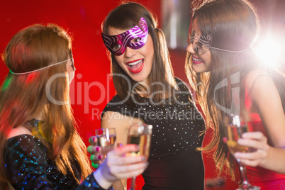 Friends in masquerade masks drinking champagne