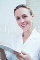 Smiling female dentist holding clipboard