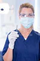 Dentist in mask holding dental explorer