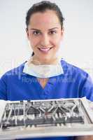 Smiling dentist holding tray with equipment
