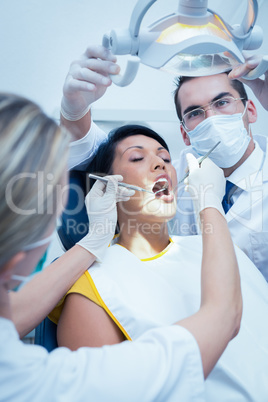 Dentist with assistant examining womans teeth