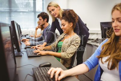 Attractive teacher helping her student in computer class