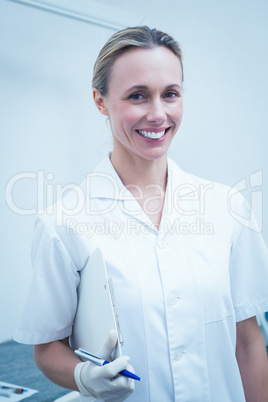 Smiling female dentist holding clipboard