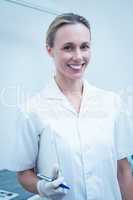 Smiling female dentist holding clipboard