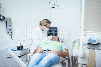 Female dentist examining mans teeth