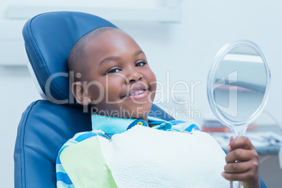 Boy holding at mirror in the dentists chair