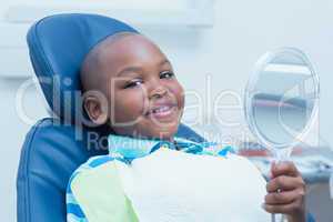 Boy holding at mirror in the dentists chair