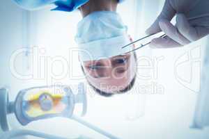 Female dentist in surgical mask holding dental tool