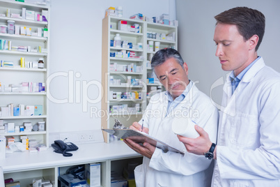 Pharmacists holding medication and writing a prescription
