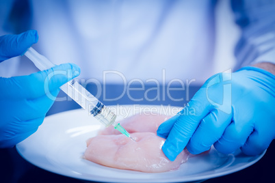 Food scientist injecting raw chicken