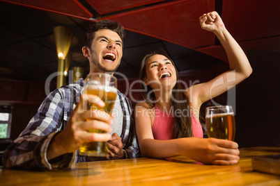 Happy friends drinking beer and cheering together