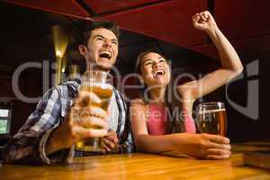 Happy friends drinking beer and cheering together
