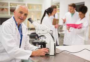 Smiling medical professor working with microscope