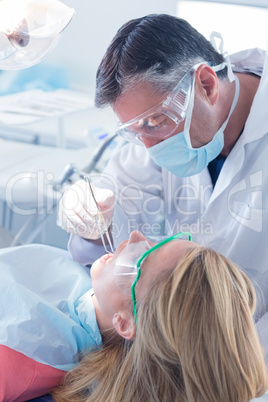 Dentist in surgical mask and gloves holding tool