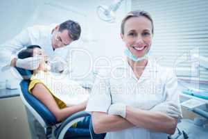 Smiling female dentist with assistant examining womans teeth