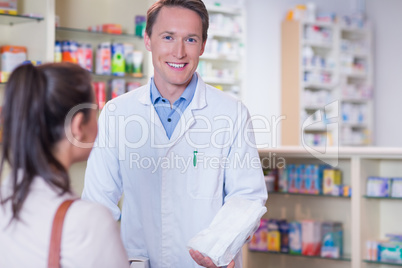 Smiling pharmacist holding a paper bag looking at camera