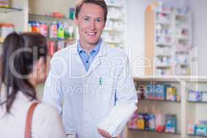 Smiling pharmacist holding a paper bag looking at camera