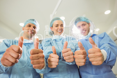 Team of surgeons looking at camera showing thumbs up