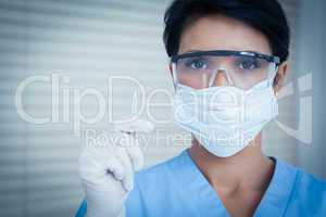 Dentist in surgical mask holding dental tool