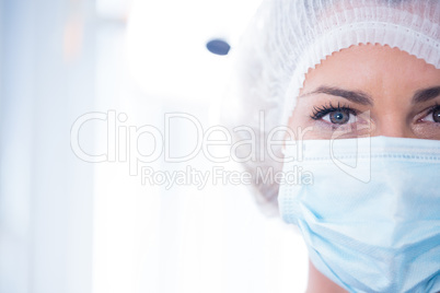 Dentist in surgical mask and cap looking at camera