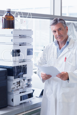 Scientist standing in lab coat holding a document