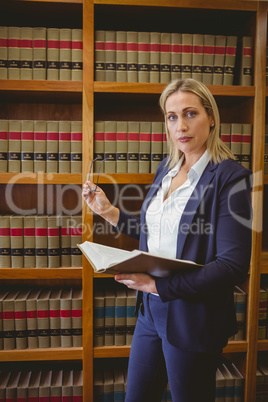 Focused librarian holding book and reading glasses