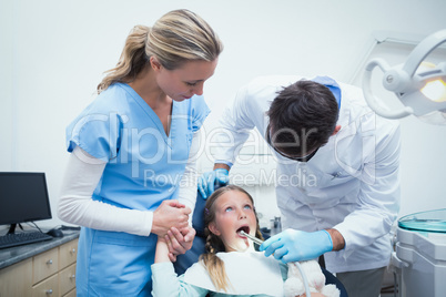 Dentist with assistant examining girls teeth