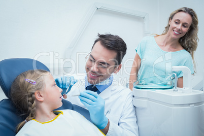 Dentist examining girls teeth with assistant