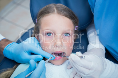 Dentist with assistant examining girls teeth