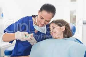 Pediatric dentist explaining to young patient how use toothbrush