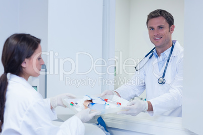 Doctor giving tray with blood sample to his colleague