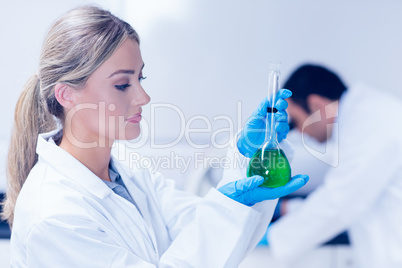Science student holding green chemical in beaker