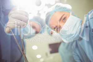 Young surgeons looking down at camera holding clamp