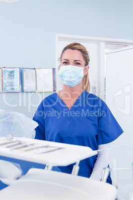 Dentist in mask behind tray of tools