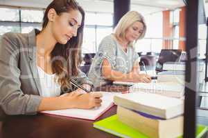 Matures females students writing notes at desk