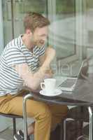 Smiling student using laptop in cafe