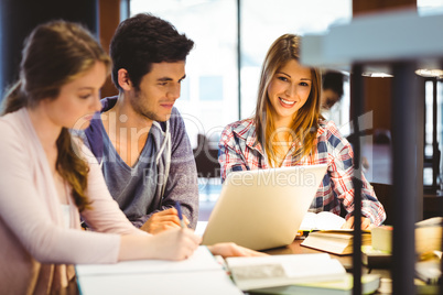 Student looking at camera while studying with classmates Student looking at camera while studying with classmates
