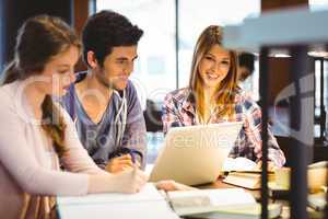 Student looking at camera while studying with classmates