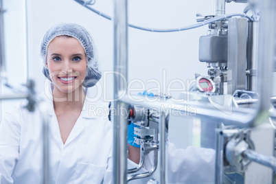 Portrait of a smiling scientist behind metal pipe