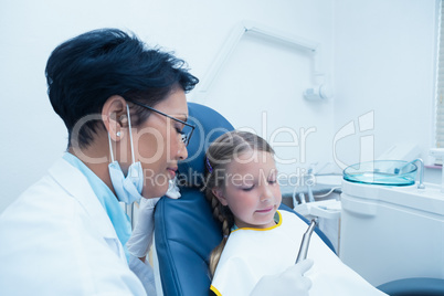 Female dentist examining girls teeth