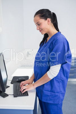 Smiling dentist typing on keyboard