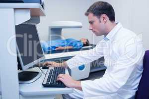 Doctor looking his computer while proceeding a radiography