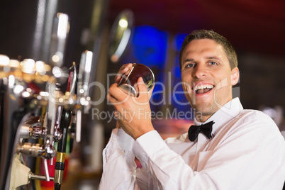 Handsome barman smiling at camera making a cocktail