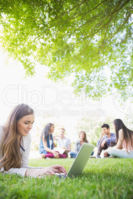 Happy student using her laptop outside