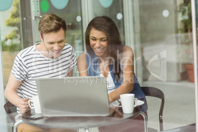 Smiling friends with chocolate cake using laptop